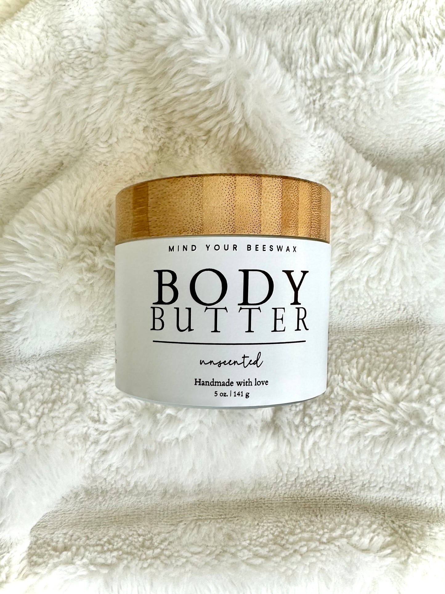 Mind your beeswax body butter in a white and gold tub.